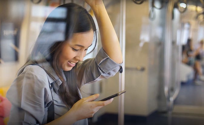 woman looking at phone riding public transport.