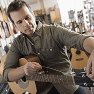 Man replacing strings on guitar.