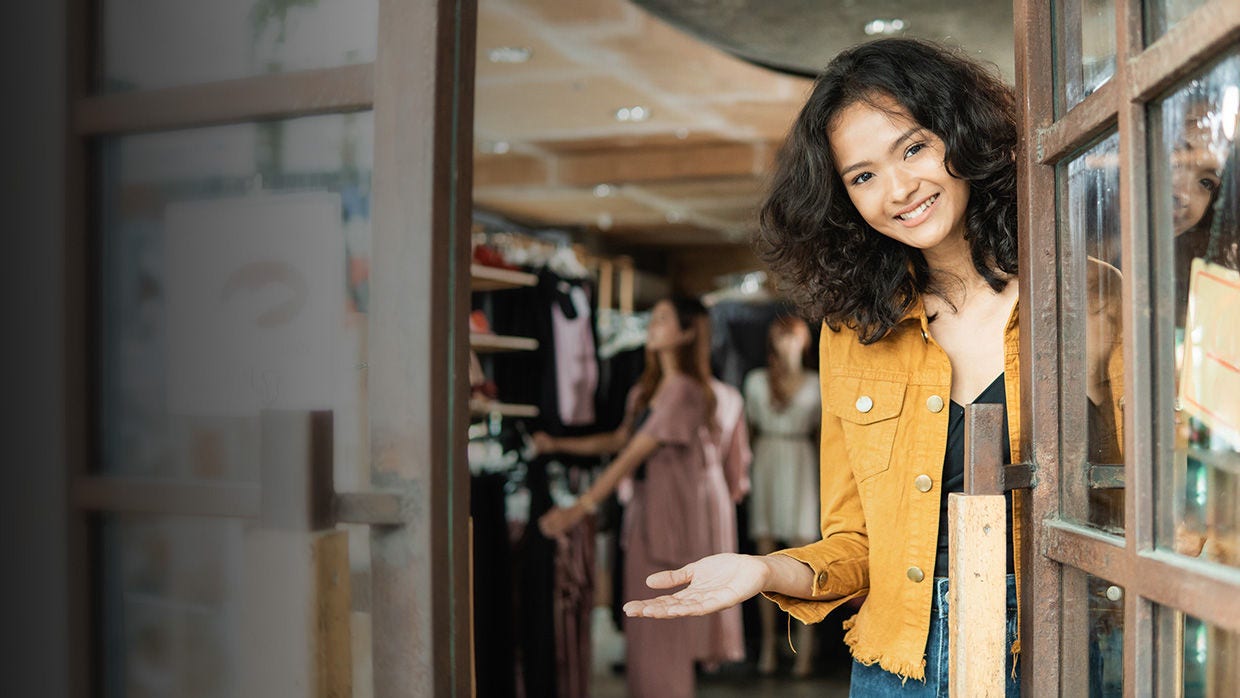 A woman stands outside a store window, looking at the products showcased inside.