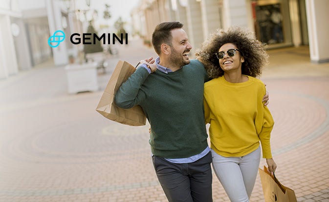 A cheerful couple shares a moment of laughter while carrying shopping bags in a marketplace.