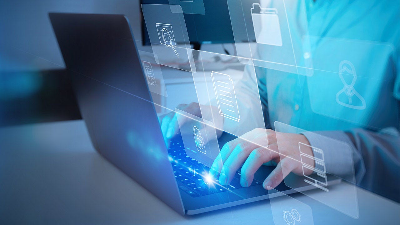 Businessman working on laptop with icons on virtual screen.