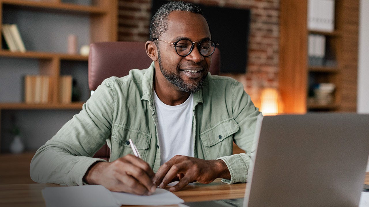Middle aged man in glasses working on laptop in home office.
