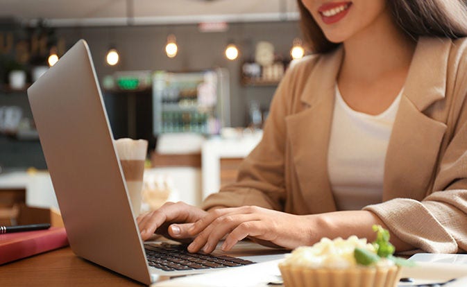 A woman focused on her laptop, typing intently with a thoughtful expression on her face.