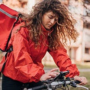 woman delivery partner riding bike and looking at phone.