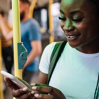 A person smiling at a smartphone inside a bus