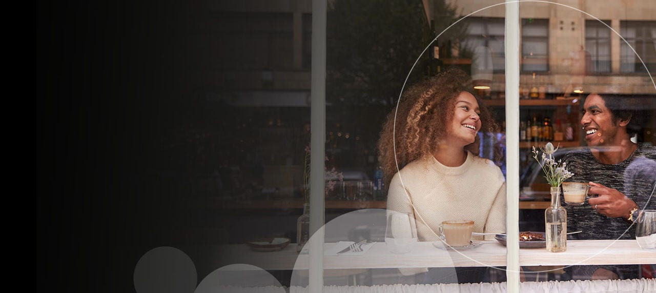 Woman smiling looking at someone next to her facing out a window.