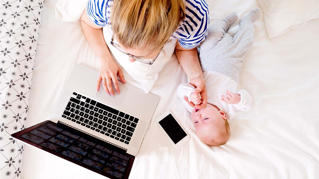 Mother with baby next to a laptop and mobile phone.
