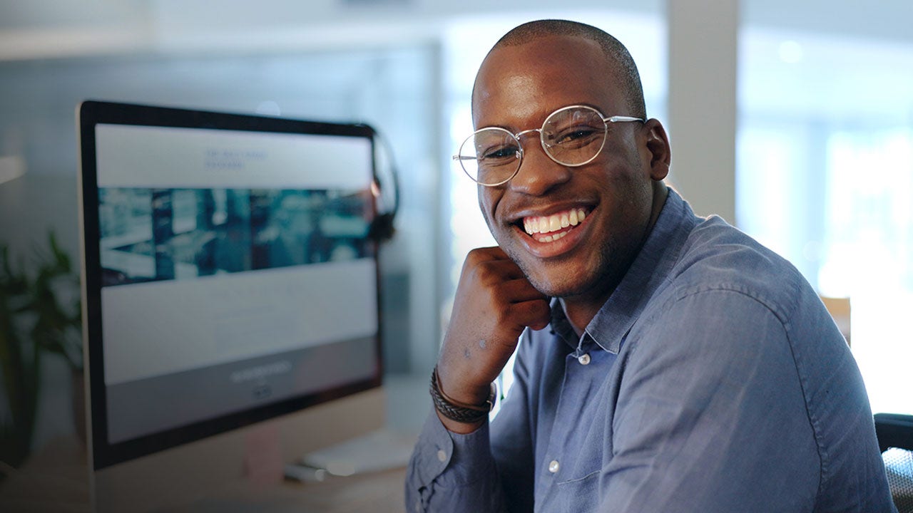 Smiling man in glasses, working in office.