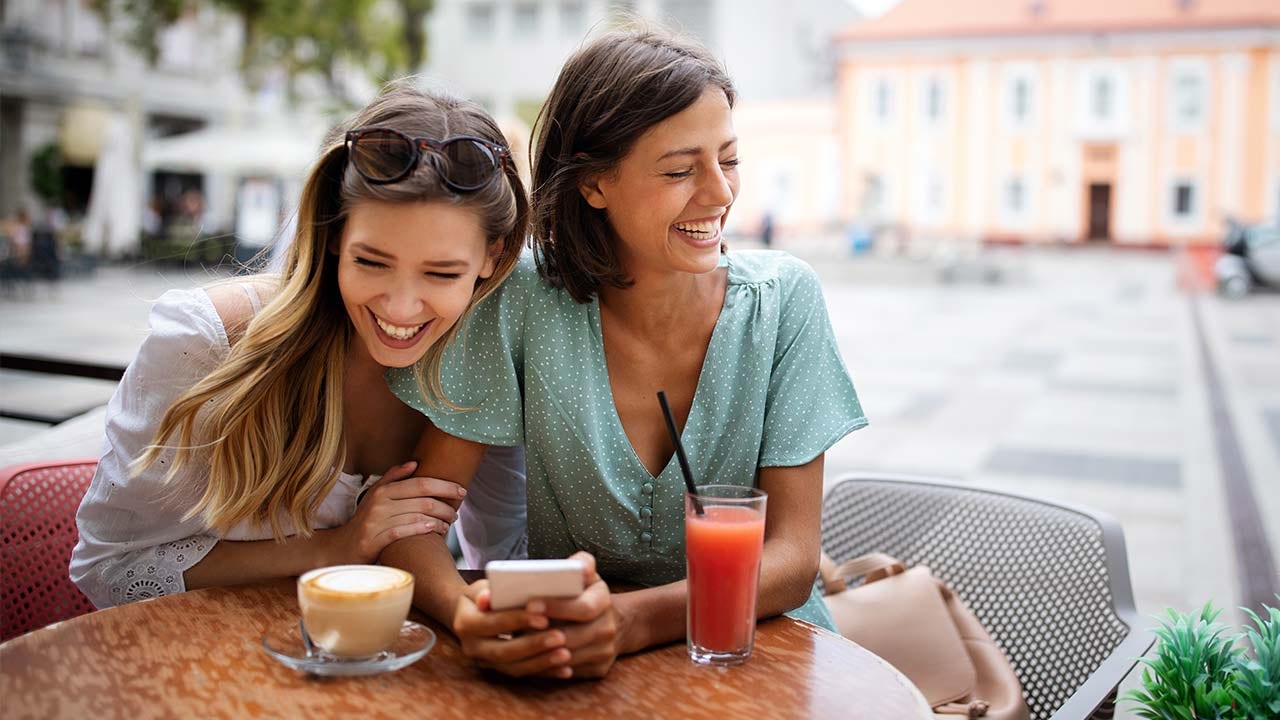 Two friends laughing at a cafe.