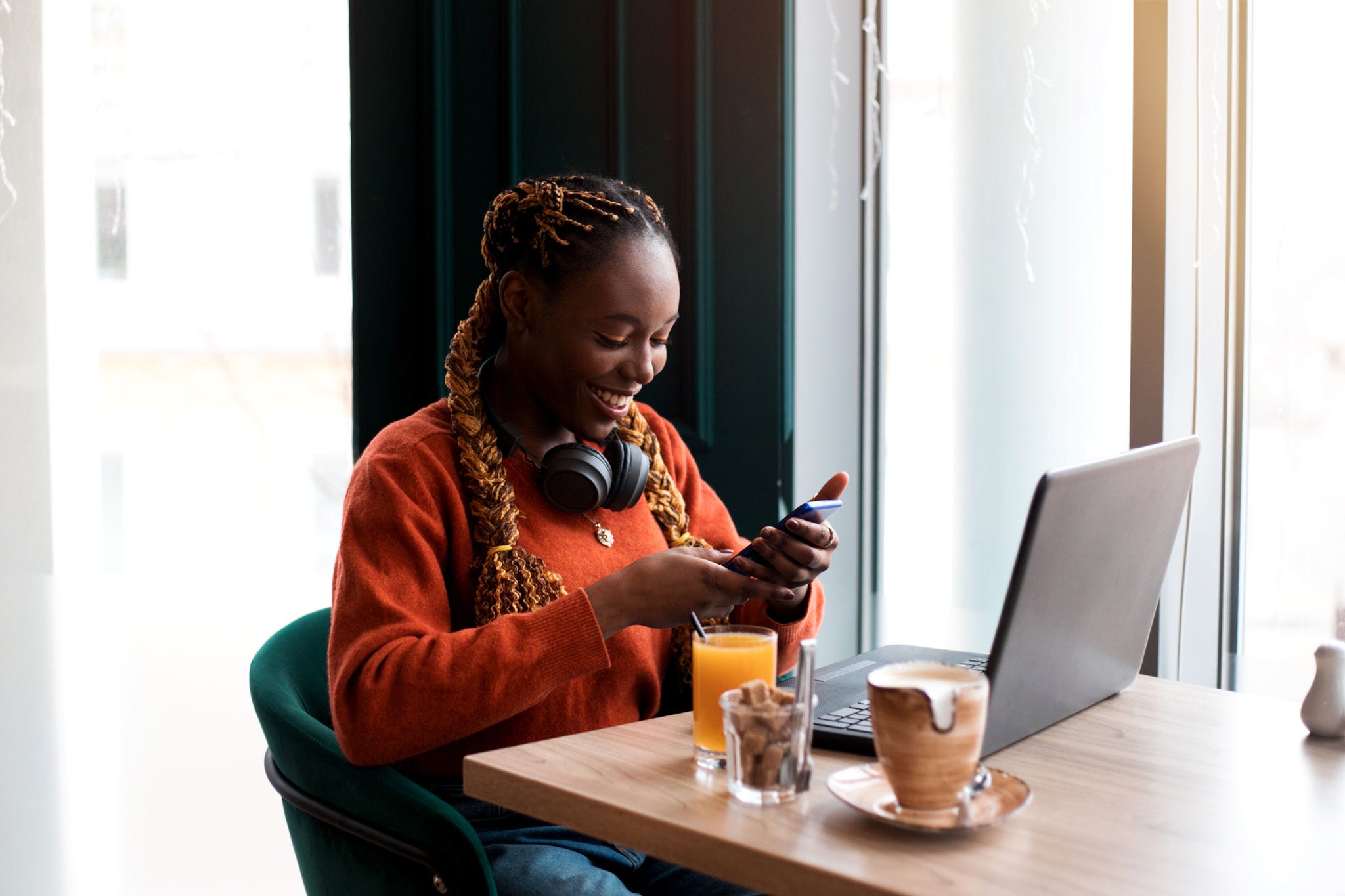 Close-up portrait of smiling young african businesswoman using smartphone in cafe.