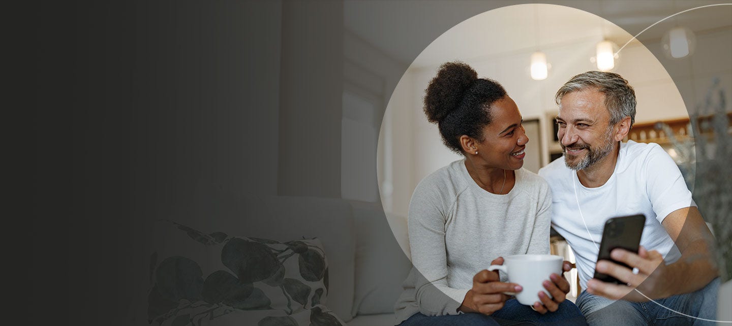 Man and woman looking at a phone and smiling.
