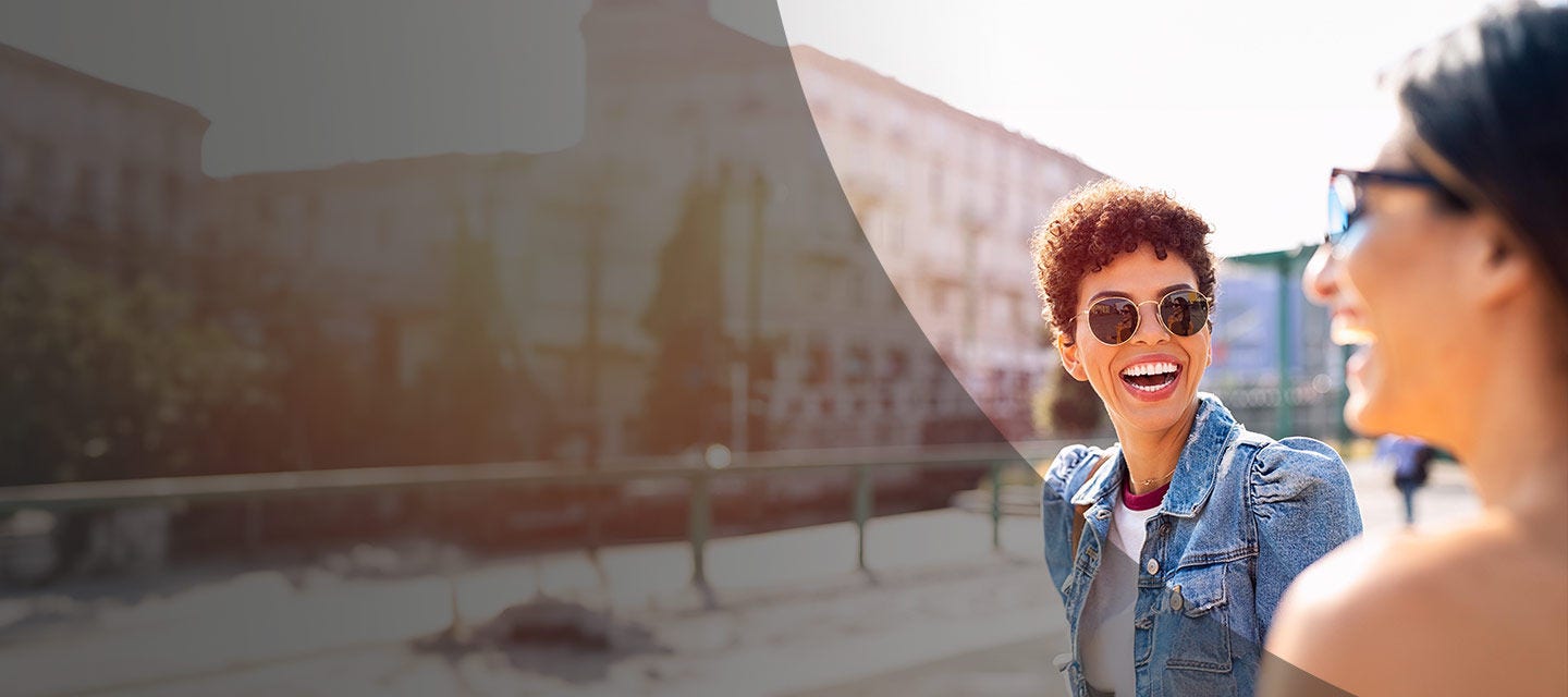 Two people smiling on a street.