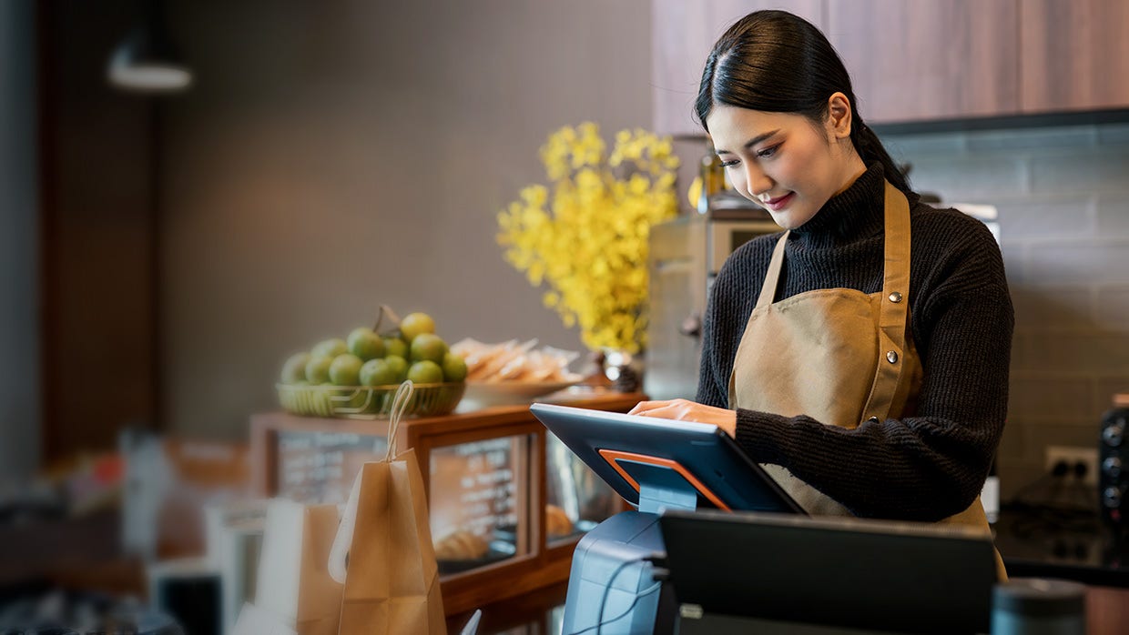 Young woman wearing apron at point of sale terminal.
