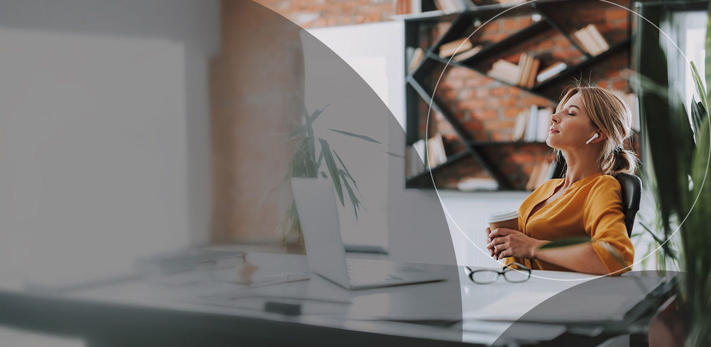 Woman relaxing at her desk with her eyes closed, enjoying a peaceful moment.
