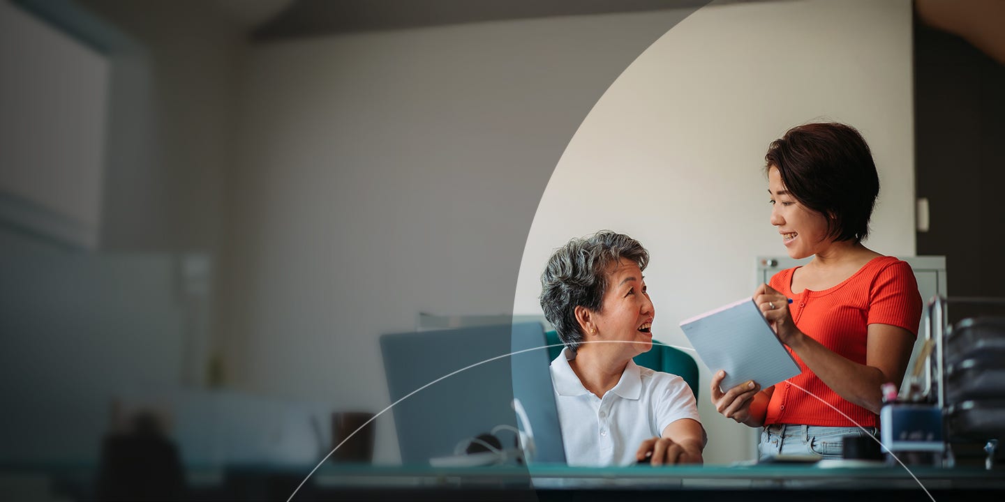 Two employees discussing bills with a notepad and a laptop.