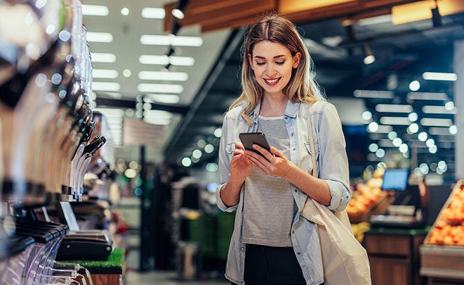 woman smiling while using her smartphone in a public space