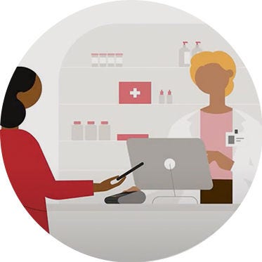 A pharmacist assisting a customer at the pharmacy counter, surrounded by shelves of medication and health products.