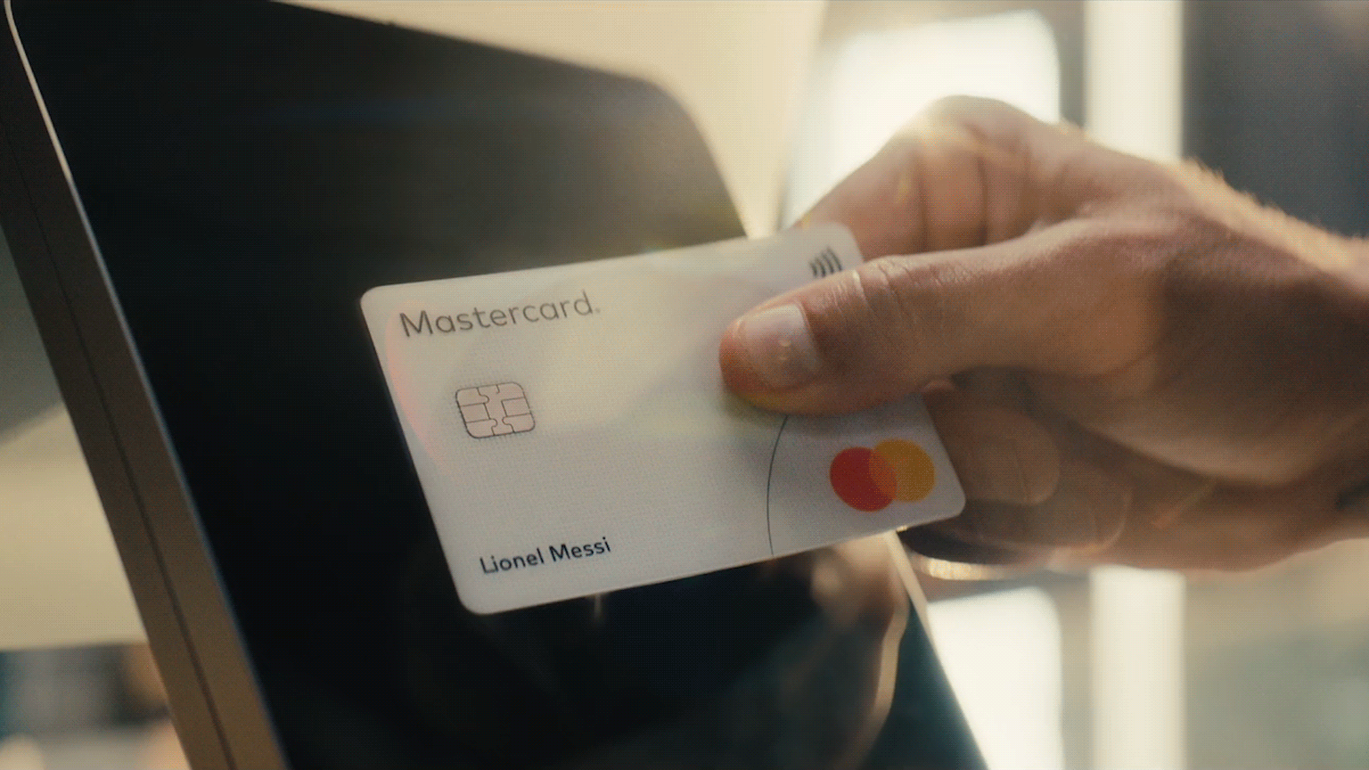 Hand tapping Mastercard on screen.